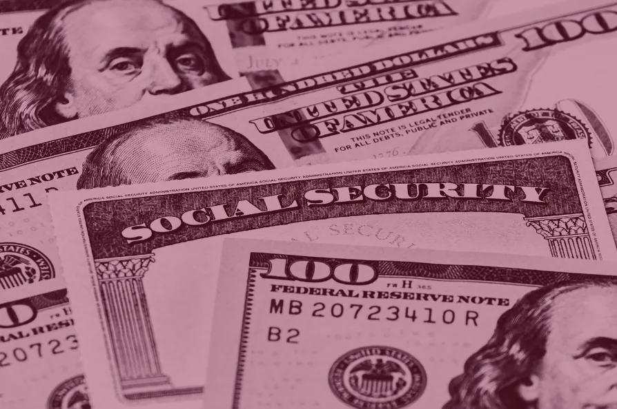 Red-tinted close-up of a Social Security card resting on hundred-dollar bills.