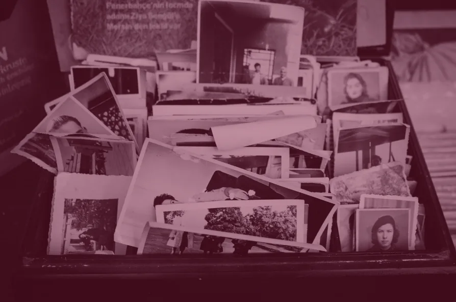 Red-tinted photo of a box filled with old family photographs.