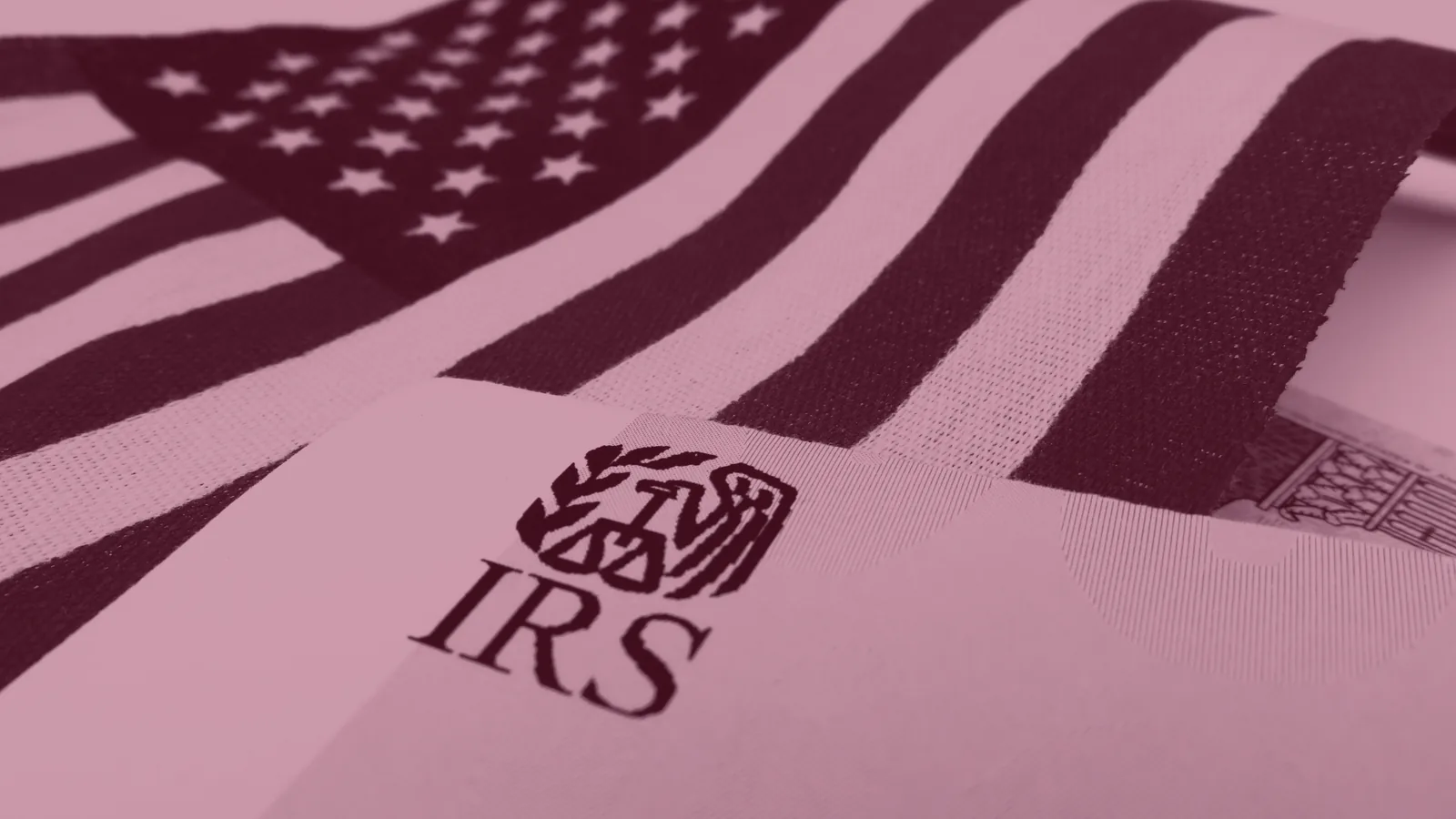 Red-tinted close-up of an IRS logo on a document beside an American flag.